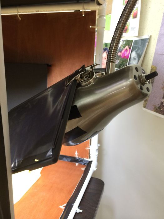 Clip on lamp with black tape over decorative holes, DVD cover attached to it with magnetic clamps